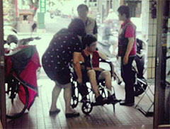 志工協助乘坐輪椅的身障人士進入辦事處